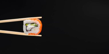 Canlı suşi seti, yaratıcı fikir. Çubuklu suşi, California ya da Philadelphia suşisi. Geleneksel Japon mutfağı kavramı. Susam tohumları serpiştirilmiş. Siyah arkaplanda.