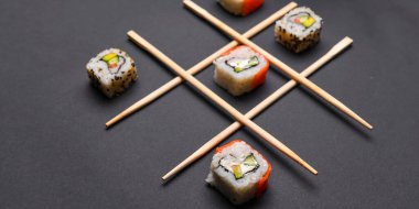 Siyah arka planda suşi, yaratıcı konsept suşi ruloları olan Tic Tac toe oyunu. Banner, tic tac toe oyunu oynuyor. Japon mutfağı konsepti, suşi reklamı..