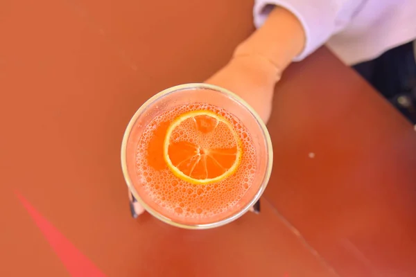 Attractive girl drinking cocktail in a bar or restaurant. Still life, refreshing alcohol drink. Fruit beverage in a bar. Young woman sitting at table.