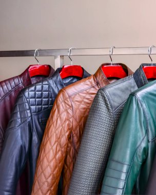 Mağazadaki askıda asılı siyah ve taçlı erkek giysileri. Erkekler için farklı renkte yay deri ceket koleksiyonu. Kapatın. Mevsimlik giysiler indirimde. Düşük fiyat, çeşitlilik.