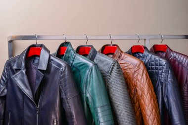 Mağazadaki askıda asılı siyah ve taçlı erkek giysileri. Erkekler için farklı renkte yay deri ceket koleksiyonu. Kapatın. Mevsimlik giysiler indirimde. Düşük fiyat, çeşitlilik.