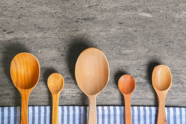 Wooden spoons with napkin on a rustic wooden table. Flat lay, top view, copy space banner. Wooden vintage cutlery.