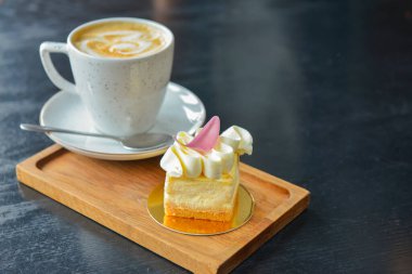 Bir fincan kahve ve tarçınlı hafif vanilyalı tatlı siyah ahşap masanın üzerindeki ahşap tahtada servis ediliyor. Kahve zamanı, tatlı tatlı atıştırmalık.