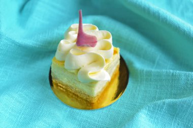 Açık mavi turkuaz masa örtüsünün üzerine konmuş, üzerinde çırpılmış krema olan hindistan cevizli vanilyalı kek. Çay saati ya da kahve saati için lezzetli bir tatlı..