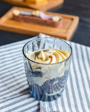 Bardakta krem şanti ile servis edilen dut ve mascarpone tatlı. Restoran tatlısı mavi masa örtüsünün üstünde. Lezzetli tatlı yemek..