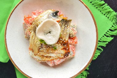 Füme somon, domates, biber ve susam tohumlu deniz ürünleri salatası. Restoran yemeği. Siyah ahşap masa ve yeşil masa örtüsünün üzerinde servis edilir..