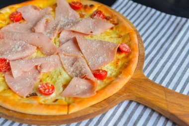 Pastırmalı, salamlı ve sebzeli pizza. Erimiş peynirli jambon ve domatesli pizza. Yakın çekim, geleneksel İtalyan mutfağı konsepti..