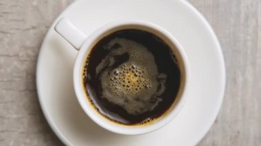 Kahve fincanda. Hafif ahşap masa arkaplanının üzerinde küçük beyaz bir fincanda Espresso kahvesi. Kahvaltı konsepti, sade kahve ve beyaz bardak. Seçici odak, kapat.