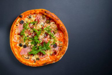 Sıcak, lezzetli, siyah arka planda ev yapımı Amerikan pizzası. Düz yerde, üst tarafta. Geleneksel İtalyan mutfağı kavramı. Salamlı pizza, mantar, zeytin. Boşluk afişini kopyala.