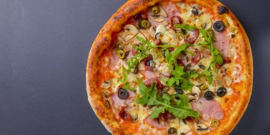 Sıcak, lezzetli, siyah arka planda ev yapımı Amerikan pizzası. Düz yerde, üst tarafta. Geleneksel İtalyan mutfağı kavramı. Salamlı pizza, mantar, zeytin. Boşluk afişini kopyala.