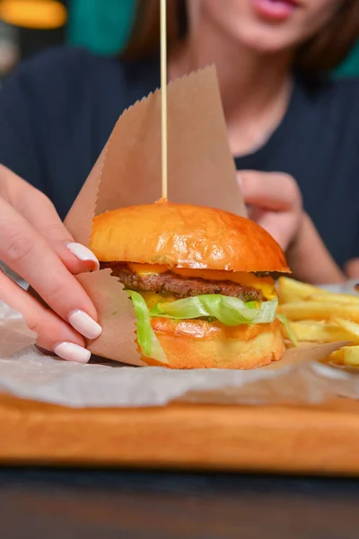 여자가 햄버거와 감자튀김을 먹으면서 있습니다 아름다운 코카서스 모델이 불분명 레스토랑 — 스톡 사진