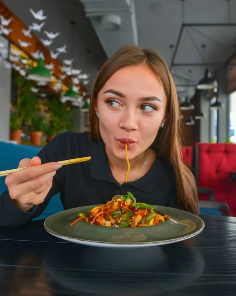 Çin yemeği yiyen genç ve güzel bir kadın. Adı da Wok ve çubukları. Et ve kızarmış kuşkonmaz tabakta. Sakin bir hayat, restoran konseptinde yemek yemek..