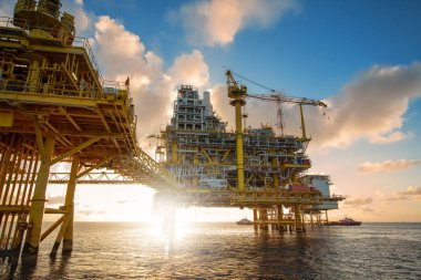 Offshore petrol platformu gündoğumu veya günbatımı zamanında. Üretim sürecinde deniz inşaatı. Dünyanın gücü enerji.
