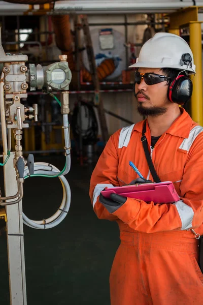 Operator or worker recording operation data of oil and gas process at production plant, Offshore oil and gas industry in the sea or gulf, Operator monitor production process and routine daily record.