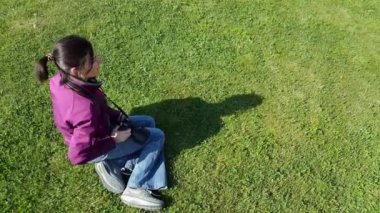 Kadın fotoğrafçı çimenlerin üzerinde DSLR fotoğraf makinesi kullanma
