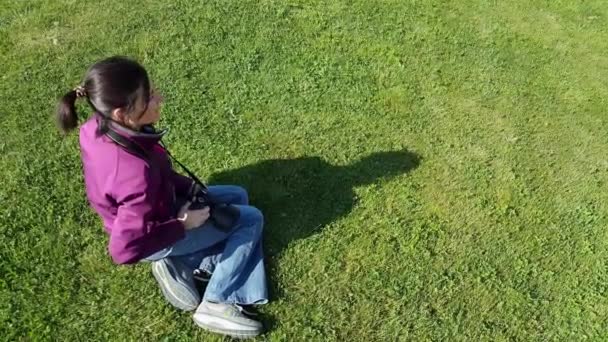Kadın fotoğrafçı çimenlerin üzerinde DSLR fotoğraf makinesi kullanma — Stok video