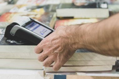 Erkek eli ödemek için kredi kartı swiping makine ile kapatın. Pos makinesi bir kitap mağazası kredi kartı kodunu girerek adam.