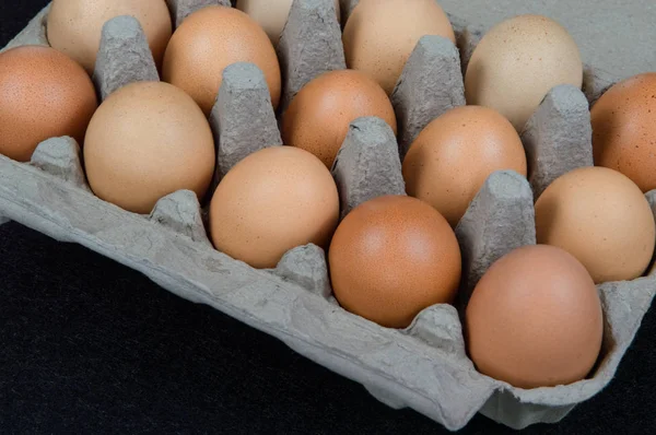 Fifteen chicken eggs in a carton box, isolated on felt mat background.