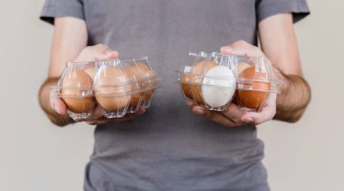 İki plastik yumurta kutusu tavuk yumurta tam tutan gri tshirt beyaz adamla.