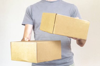 Gri tshirt beyaz bir arka plan üzerinde iki koli kutu taşıyan beyaz adamla