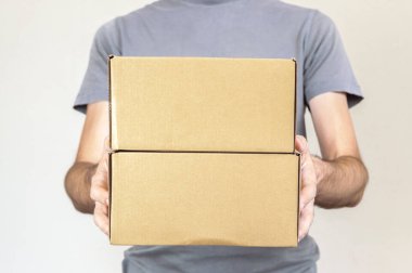 Gri tshirt beyaz bir arka plan üzerinde iki koli kutu taşıyan beyaz adamla