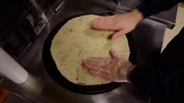 Cook siyah bir ocak üzerine krep bazı domates sosu koyarak