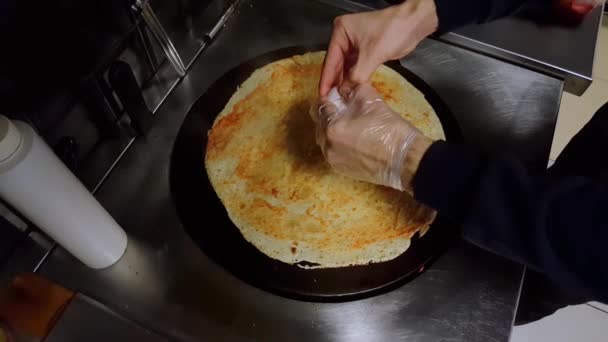 Cozinhe quebrando um ovo no crepe em um fogão preto — Vídeo de Stock