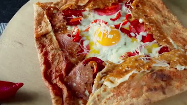 Délicieuse crêpe aux œufs, fromage et salami servie avec des assaisonnements sur une planche de bois — Video