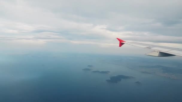 Самолет летит над морем и городом, вид из окна — стоковое видео