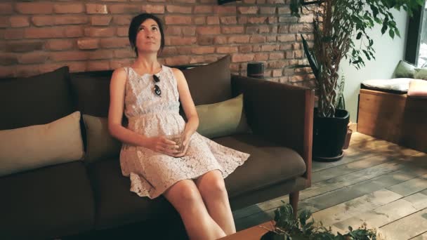 Одинокая белая женщина в платье ждет свою спутницу в кафе — стоковое видео