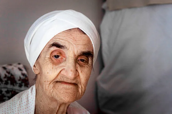Very old senior woman with bonnet sitting in her room