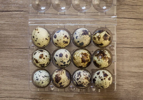Tampilan puncak telur puyuh dalam kotak plastik pada latar belakang kayu cokelat — Stok Foto