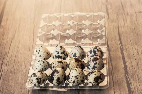 Telur puyuh dalam kotak plastik dengan latar belakang kayu cokelat — Stok Foto