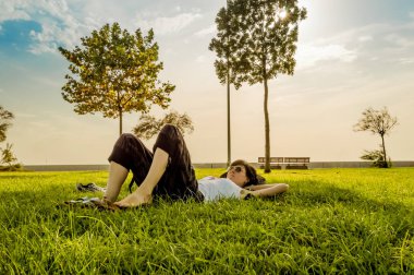Esmer kadının sırtında natu yeşil çim üzerinde yalan