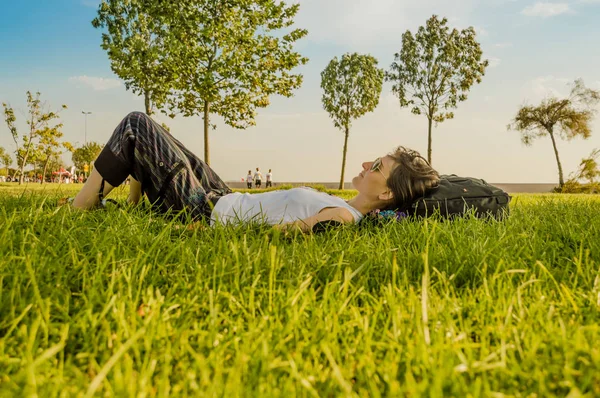 Brunett kvinna njuter liggande på rygg på grönt gräs i natu — Stockfoto