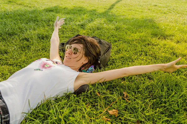 Brunett kvinna njuter liggande på rygg på grönt gräs i natu — Stockfoto