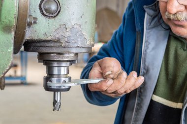 Atölyede frezeleme makinesi kullanan mavi yakalı işçi