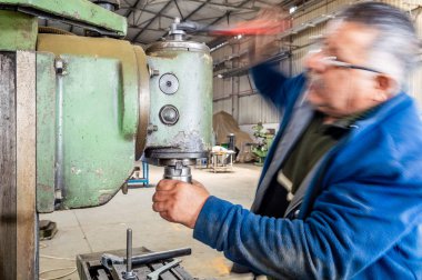 Atölyede frezeleme makinesi kullanan mavi yakalı işçi