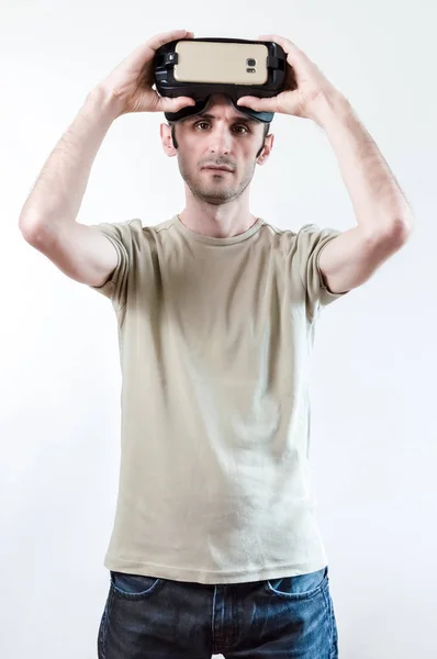 Retrato de um homem morena bonito com óculos de realidade virtual na cabeça no fundo branco — Fotografia de Stock