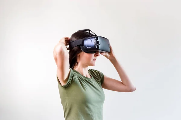 Mujer morena explorando la tecnología moderna realidad virtual con pantalla montada en la cabeza sobre fondo blanco —  Fotos de Stock