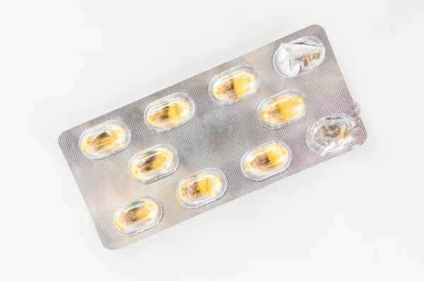 Capsules jaunes emballées dans une plaquette thermoformée isolée sur fond blanc — Photo