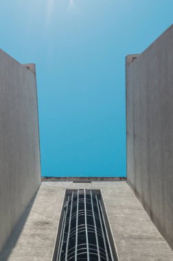 Mavi gökyüzü olan bir binanın sarmal yangın merdiveni alçak açılı..