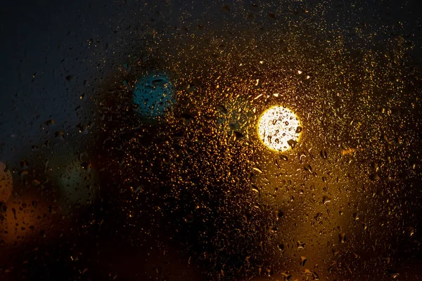 밤에는 도시의 창문에 빗방울들 색광으로 추상적 배경을 흐리게 하였다 — 스톡 사진