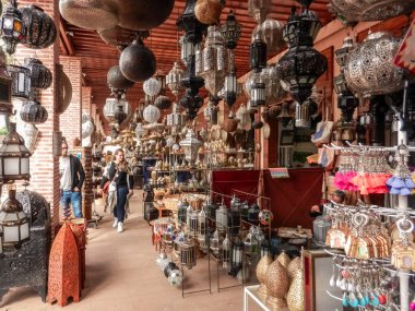 Marakeş, Fas - 30 Ekim 2018: Marakeş, Fas 'ta hediyelik eşya dükkanlarının yakınında yürüyen turistler çeşitli türde lambalar ve hediyeler satıyorlar.