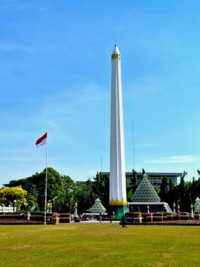 Surabaya, Endonezya, 7 Eylül 2023 Tugu Pahlawan anıtı ve kırmızı ve beyaz bayrak Surabaya halkının sömürgecileri sınır dışı etme mücadelesini anmaktadır. Önplandaki yeşilliğin görünümü, göz seviyesindeki perspektif.