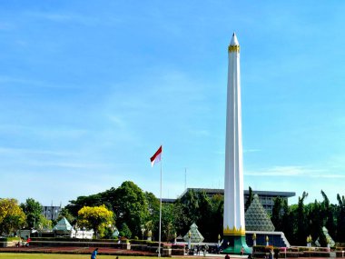 Surabaya, Endonezya, 7 Eylül 2023 Tugu Pahlawan anıtı ve kırmızı ve beyaz bayrak Surabaya halkının sömürgecileri sınır dışı etme mücadelesini anmaktadır. Önplandaki yeşilliğin görünümü, göz seviyesindeki perspektif.