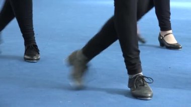 İnsanlar müzik festivalinde birlikte step dansı yapıyorlar. Tamponlar mavi kata çarpıyor. Step ayakkabılarını kapat, arka planda parlak bir ışık var. Klasik dans tarzı, eğlence ve müzik kültürü.
