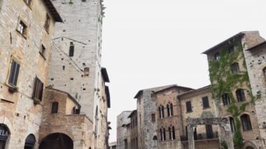 Temmuz 2018, San Gimignano, Toskana İtalya - Piazza della Cisterna 'da gezen gezginler. İnsanlar ana meydanı, ortaçağ kulelerini ve kuyuyu ziyaret ediyor. İtalyan bayramı, turizm, turizm beldesi