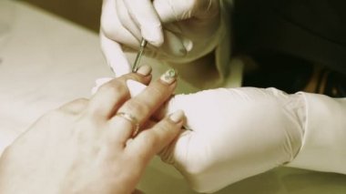 Manikürcü kütikül itici kullanarak.