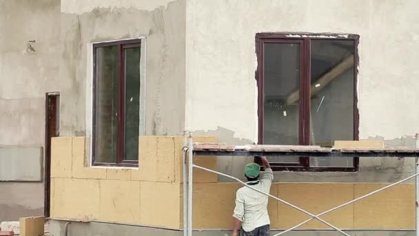 Worker man insulates wall outdoor building — Stockvideo